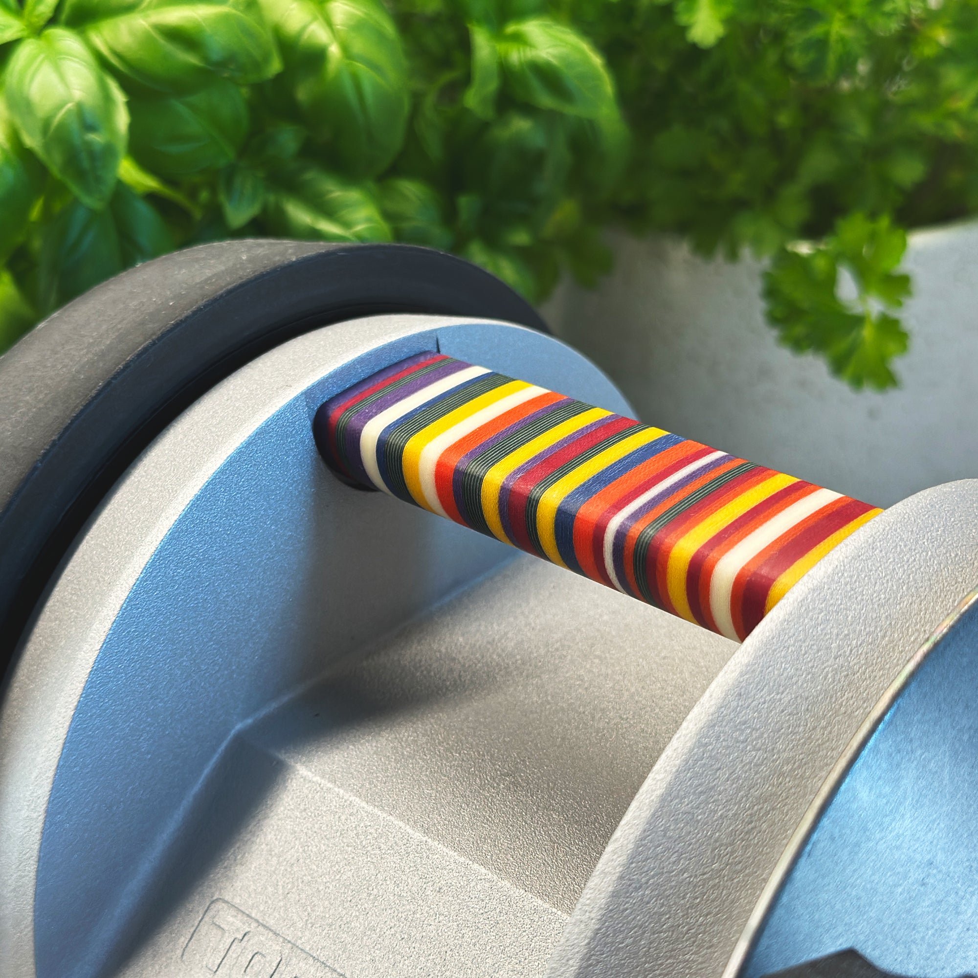 A close-up of the colorful handle of the Tormek T-1 Florentine Vibrant with herbs in the background